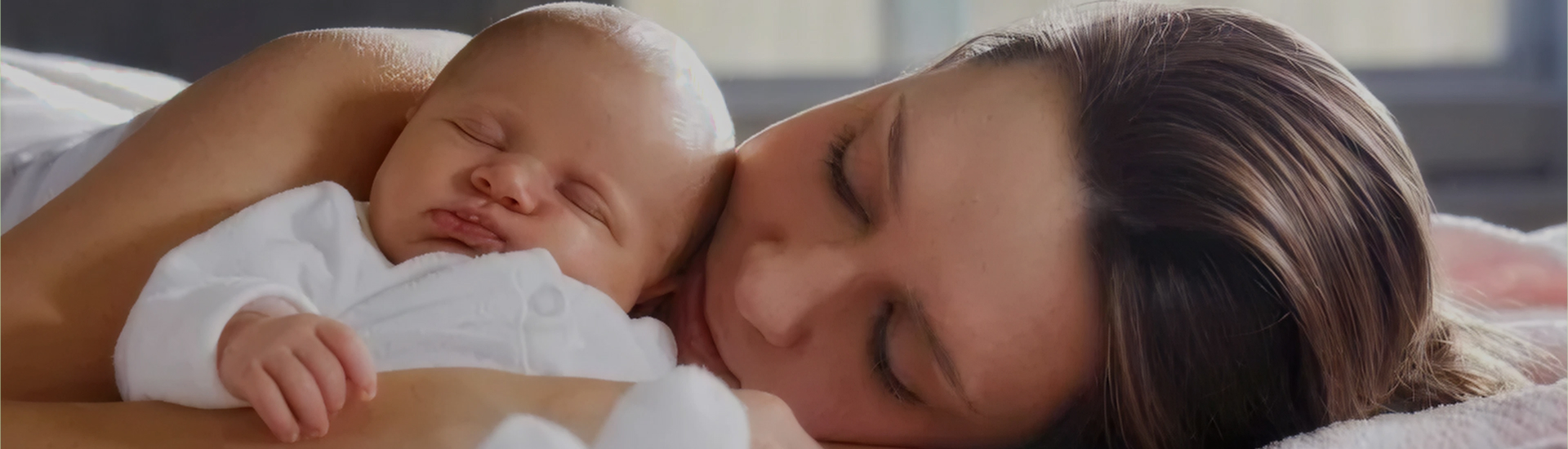 A mother rests peacefully beside her newborn baby, both lying close with eyes closed—capturing the serenity, bonding, and deep connection of the postpartum period.