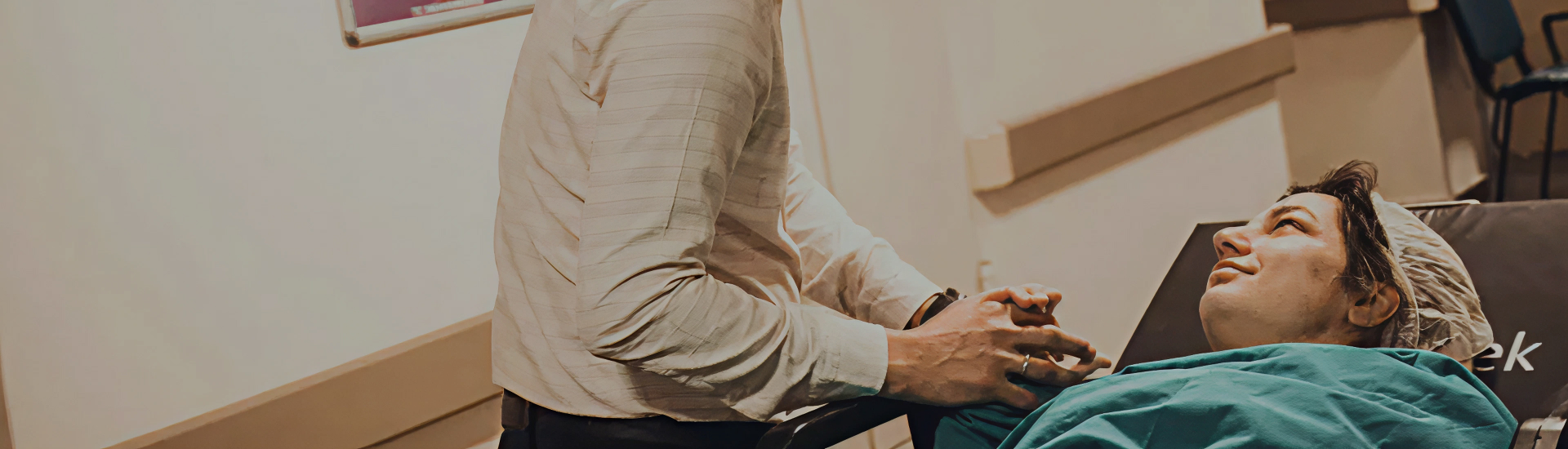 A supportive partner holds the hand of a person in a hospital bed, who smiles up at them—capturing connection, reassurance, and emotional presence during a significant medical or birth experience.