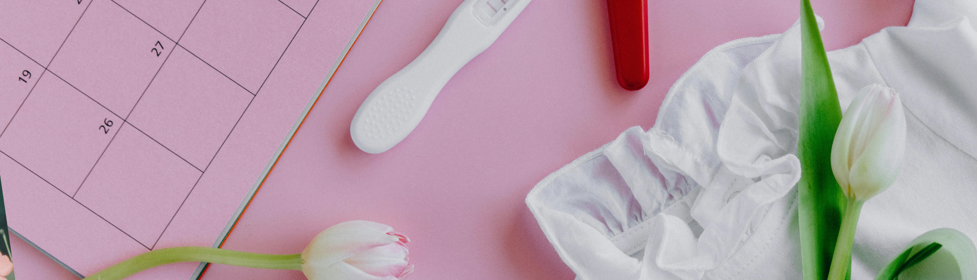 Pregnancy test and calendar grouped together symbolizing infertility
