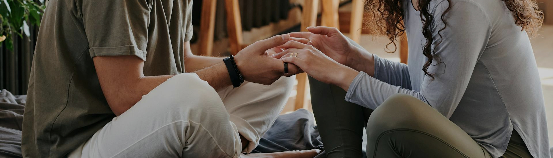 Two people sit close together, gently holding hands in a moment of connection and care—symbolizing emotional support, vulnerability, and compassionate communication.