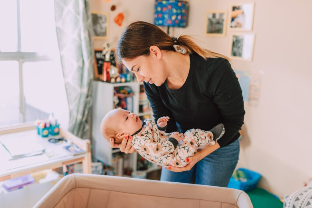 A parent gently holds and looks lovingly at their baby in a cozy, sunlit nursery—capturing connection, responsiveness, and the nurturing rhythm of early parenting.